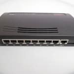 Network switch or router device on a plain white surface, used for internet and network connectivity in a home or office setting.