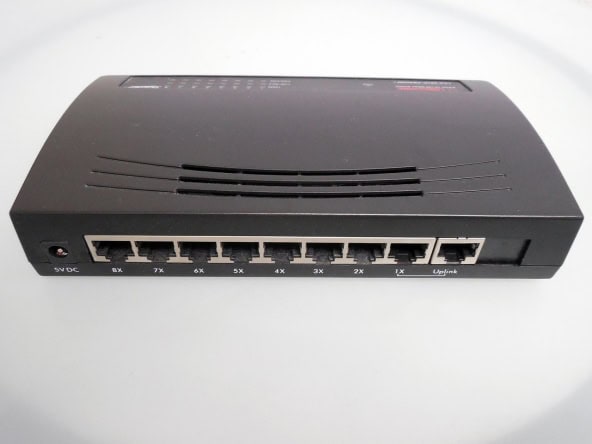 Network switch or router device on a plain white surface, used for internet and network connectivity in a home or office setting.
