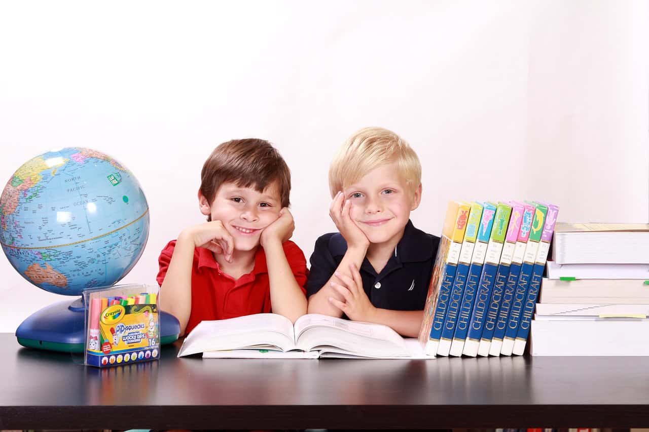 Playful young children reading books at school with globe and art supplies for educational activities in Javea, Spain.