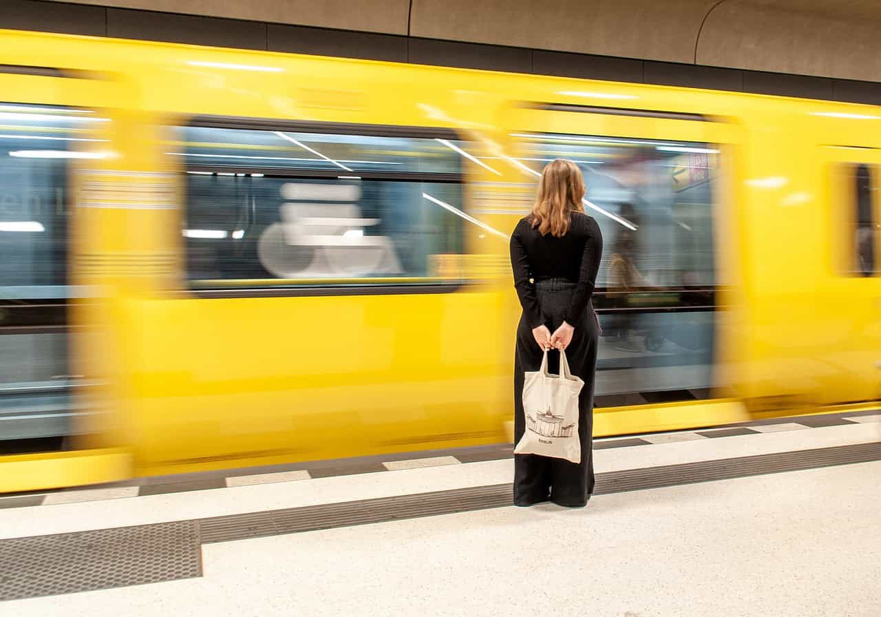 Yellow tram in metro station with woman waiting, urban transportation, Madrid public transit, commuting station, city transportation infrastructure.